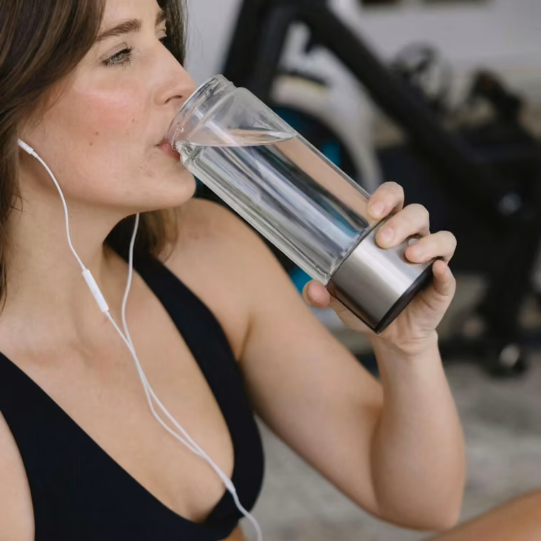Vrouw drinkt Aquivor waterstofwater tijdens haar training